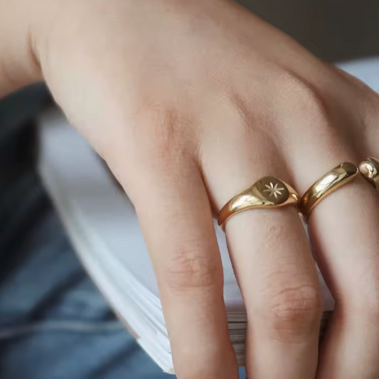 Close-up of a hand wearing two gold rings with star designs.