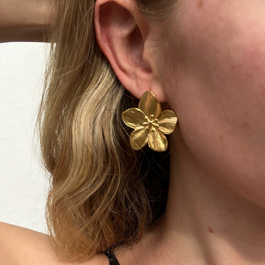 statement gold flower earrings on a women